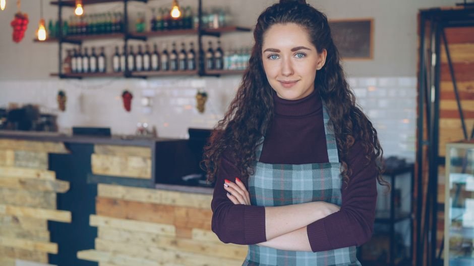 Café-ejer står smilende bag disken